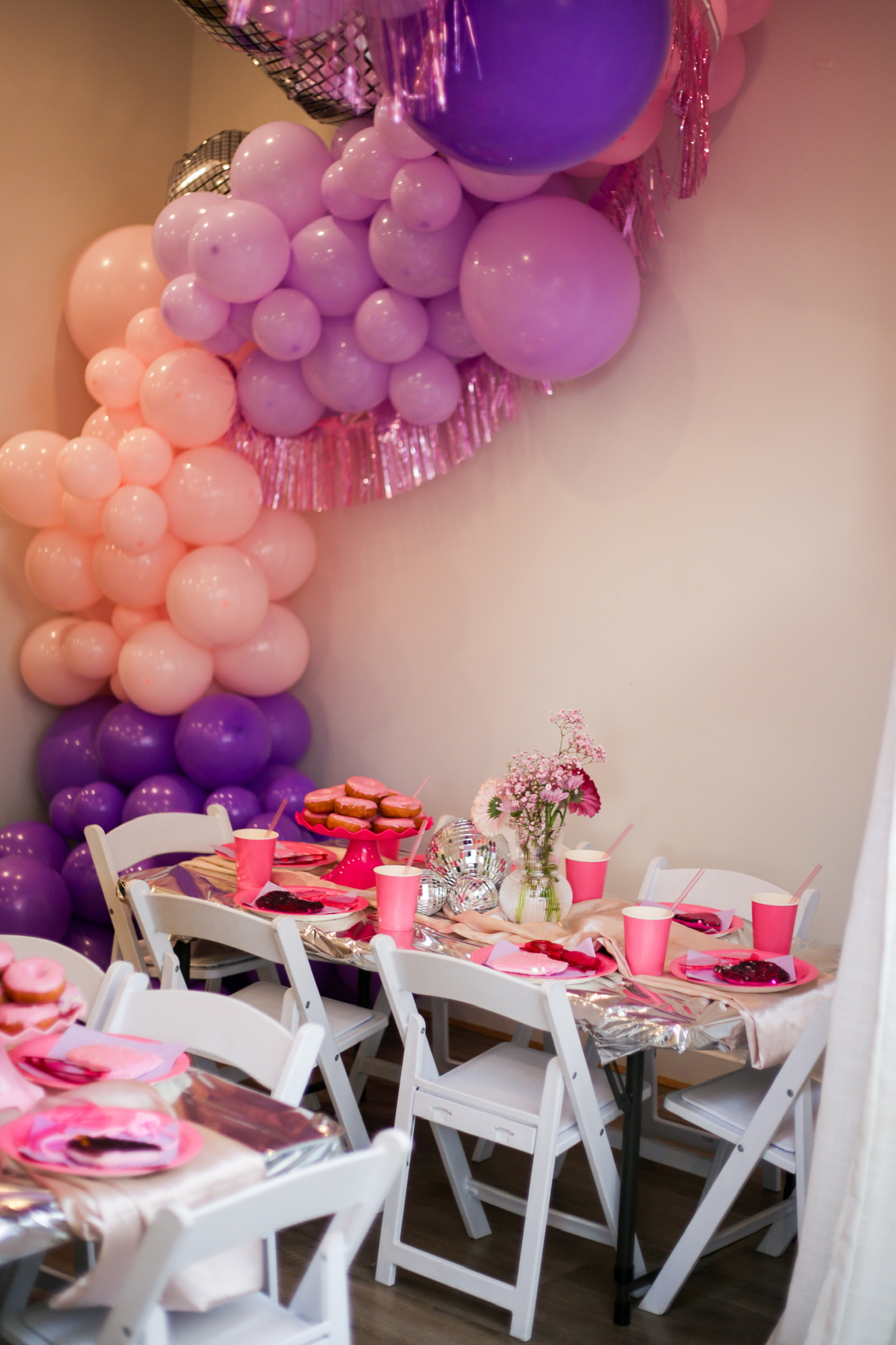 Pink and purple balloon garland styling behind a first birthday party table