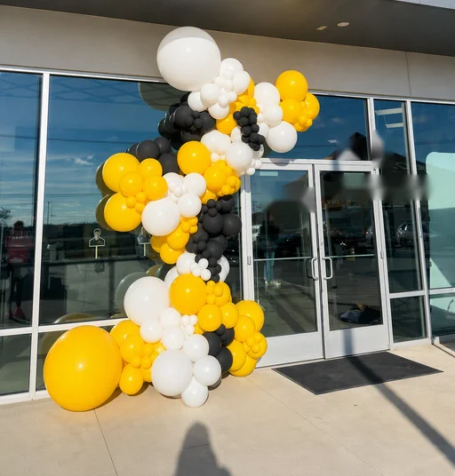 Yellow, white and black balloon garland at a building entrance